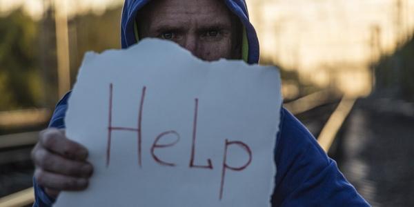 Chico con un cartel que dice 'Help' pidiendo ayuda
