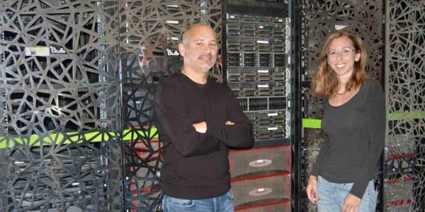 Sergi Beltrán y Leslie Matalonga posan frente al superordenador del Centro Nacional de Análisis Genómico (CNAG).