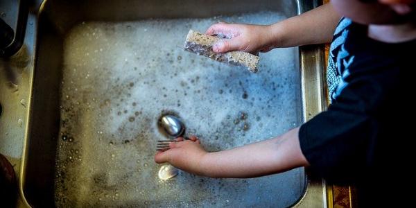 Fregar los platos son tareas que los niños pueden hacer para ayudar en casa