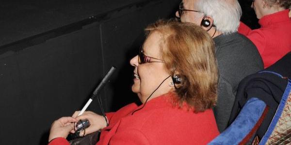 Espectadores ciegos siguen una representación teatral con un sistema de audiodescripción | Foto de ONCE