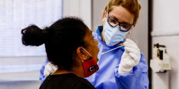 Una trabajadora sanitaria protegida realiza un test a una mujer / Marta Perez, 20minutos