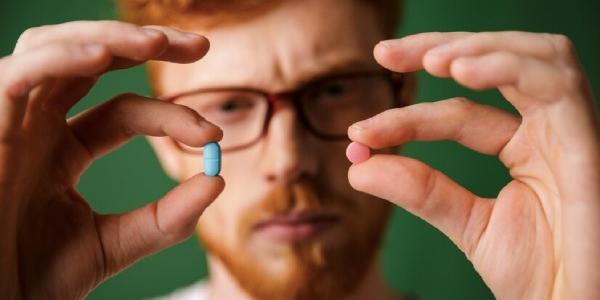 Hombre con dos pastillas, una de viagra