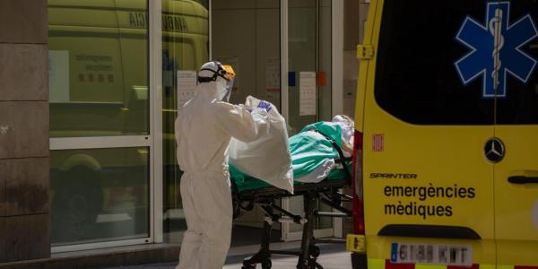 Un sanitario protegido con un traje transporta a una persona contagiada con coronavirus en una camilla (David Zorrakino / EP)